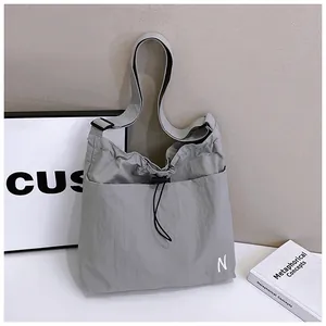 Close-up of light gray nylon drawstring tote bag with embroidered N logo and sturdy strap