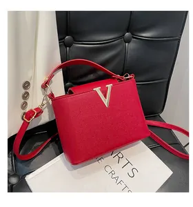 Détail d'un sac à main rouge en cuir avec une boucle dorée en forme de V et texture