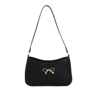 Minimalist black crocodile pattern shoulder bag with a gold metal bow accessory