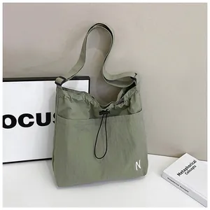 Close-up of sage green nylon crossbody bag with drawstring closure and N logo detail