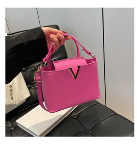 Détail du sac à main rose fuchsia avec texture litchi et grand logo en métal doré en V