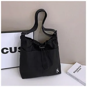 Detail of black nylon drawstring bag showing waterproof fabric and white N embroidery