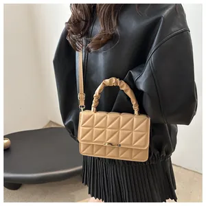 Close-up of beige quilted crossbody bag featuring cloud handle and gold metal fastener