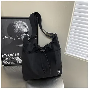 Detail view of black nylon drawstring bag showing adjustable strap and front pockets