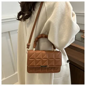 Detail view of caramel quilted crossbody bag with ruched handle and golden hardware