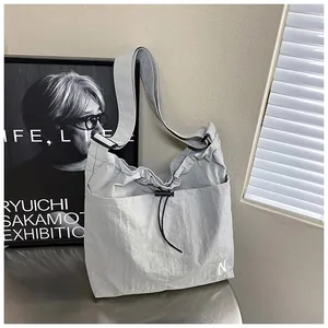 Detail of light gray nylon crossbody bag with drawstring pocket and N letter print