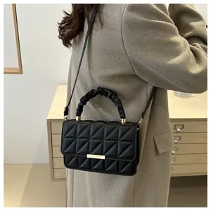 Detail of black quilted shoulder bag featuring gold clasp and ruched handle texture