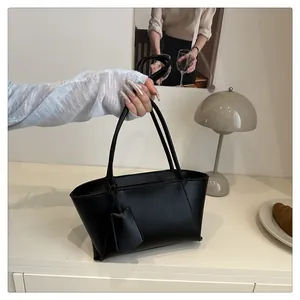 Sac fourre-tout minimaliste en similicuir noir avec pendentif tenu par une personne