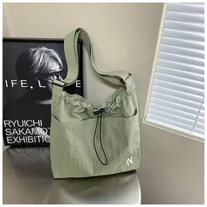 Detail of green nylon crossbody bag with drawstring closure and white letter N logo