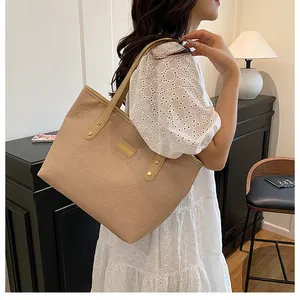 Detail of light brown tote bag with embossed geometric patterns and metal Fashion plate