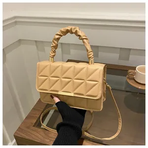 Detail of khaki quilted crossbody bag with pleated cloud handle and gold metal bar