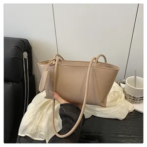 Détail du sac à bandoulière trapèze beige minimaliste avec étiquette carrée décorative