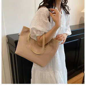 Detail of beige large tote bag with embossed geometric patterns on a fashion model