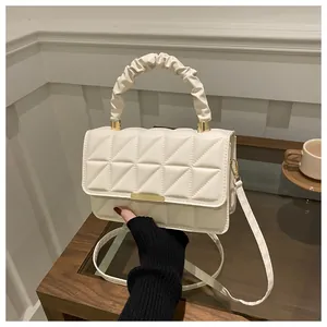 Detail of quilted beige crossbody bag with gold hardware and ruched cloud handle