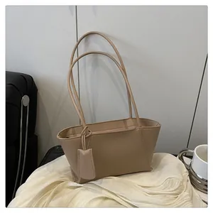 Détail du sac cabas beige minimaliste avec fines bandoulières et étiquette assortie