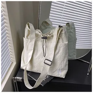 Detail of off-white drawstring crossbody bag featuring N embroidery and nylon texture