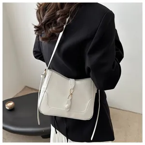 Detail view of cream white saddle bag on model with gold metal buckle and thin strap