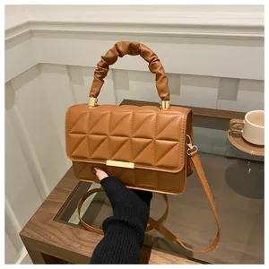 Detail of caramel quilted crossbody bag with gold hardware and ruched handle
