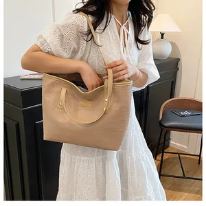 Detail of beige textured tote bag with FASHION label and long shoulder strap for women