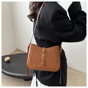 Detail of caramel faux leather shoulder bag with gold hardware worn by model