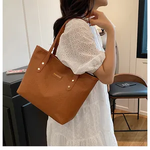 Detail of caramel embossed tote bag with gold metal logo and sleek shoulder straps
