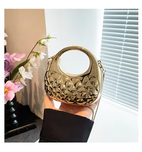 Detail of gold quilted acrylic clutch with textured diamond pattern and chain strap