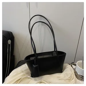 Détail d'un sac sous le bras en cuir noir mat minimaliste avec de longues lanières