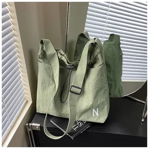 Detail of light green nylon shoulder bag featuring drawstring closure and N embroidery