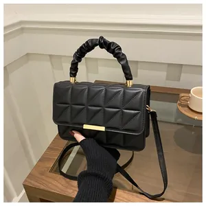Detail of black quilted crossbody bag with gold buckle and ruffled cloud handle