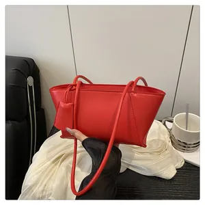Vue détaillée du sac à bandoulière trapèze rouge minimaliste avec pendentif assorti