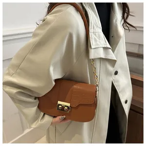Close-up of brown croc-embossed shoulder bag with gold hardware on a beige coat
