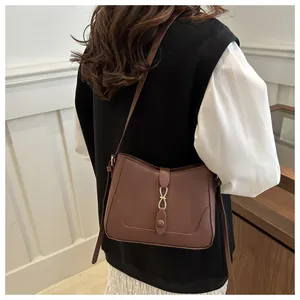 Detailed view of dark brown crossbody bag featuring elegant gold metal clasp and leather strap