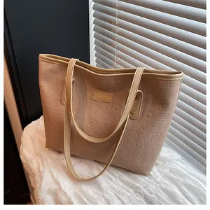 Close-up of beige tote bag featuring embossed letter patterns and a gold Fashion logo