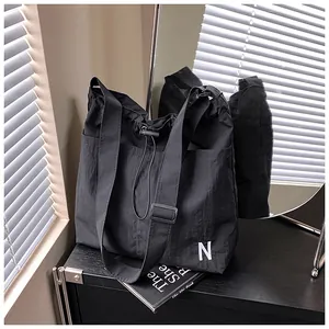 Detail of black nylon drawstring tote bag with letter N embroidery and side pocket