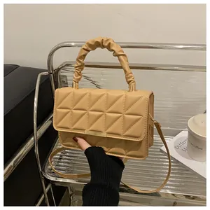 Close-up of khaki quilted crossbody bag with a pleated handle and gold hardware detail