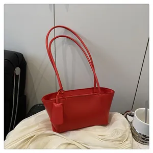 Détail macro du sac à main rouge en similicuir avec étiquette et fines lanières