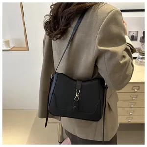 Chic black matte leather underarm bag with gold figure-eight buckle shown on a model