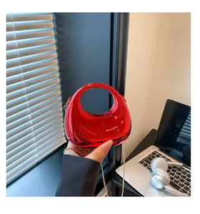 Detail of red acrylic evening bag with metallic finish and round integrated handle