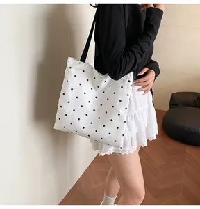 Close-up of white floral tote bag featuring black flower prints and delicate lace trim