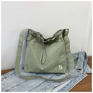 Detail of light green nylon crossbody bag with drawstring closure and letter N print