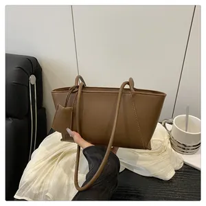 Détail du sac cabas en cuir marron foncé avec mini pochette et silhouette minimaliste