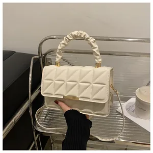 Close-up of quilted beige crossbody bag featuring a soft ruched cloud handle and gold hardware