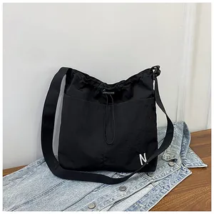 Detail of black drawstring crossbody bag with N logo on casual denim background
