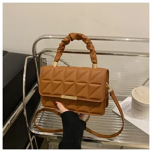 Detail of caramel quilted bag with ruched cloud handle and gold metal buckle