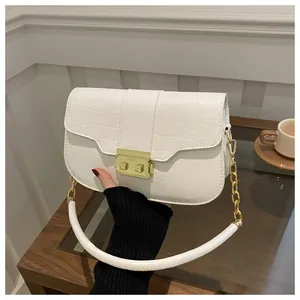 Detail shot of white crocodile pattern leather handbag with elegant gold metal buckle