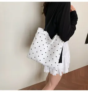 Close-up of floral canvas shoulder bag with lace trim and black straps on a model