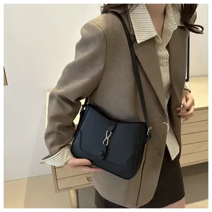 Detail of minimalist black leather underarm bag with elegant gold metal buckle closure