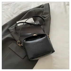 Detail view of the black pleated PU leather texture and gold hardware on the handbag