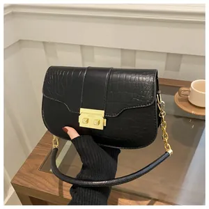 Detailed close-up of black crocodile pattern flap handbag with golden square metal lock
