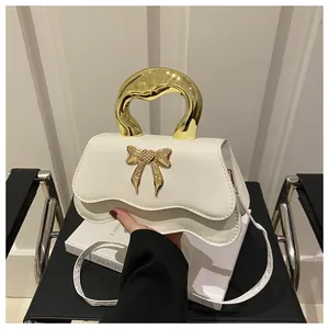 Detail of cream leather handbag with scalloped edge and golden bow-knot metal clasp